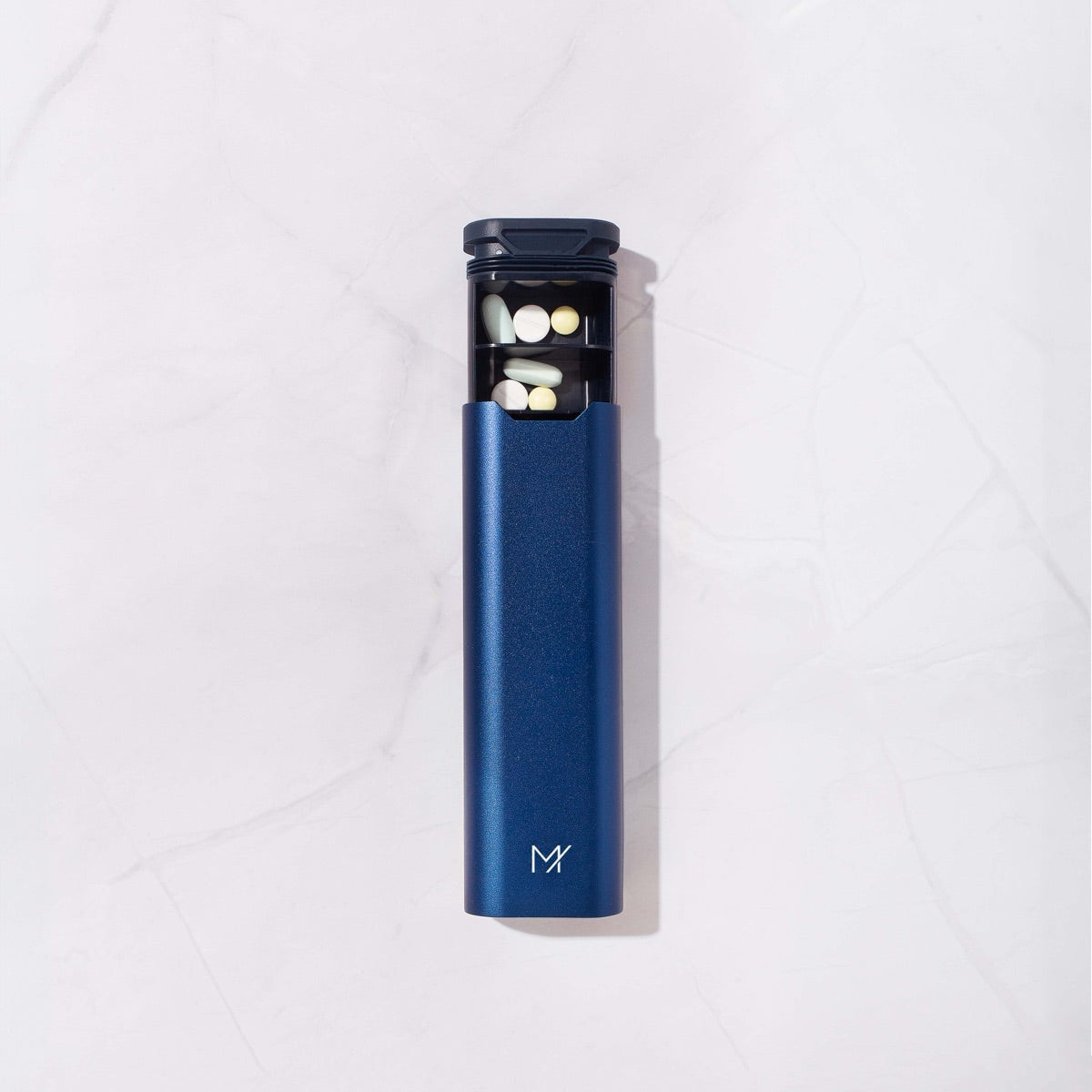 The Mannox Once-Daily pill box in navy blue, top-down with the tray part-open