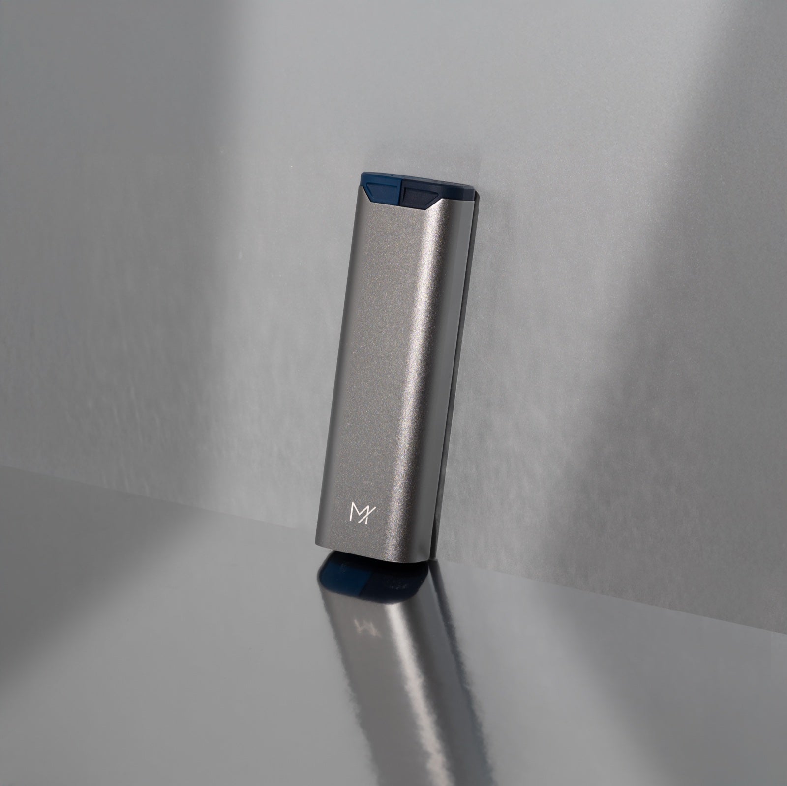 A graphite Mannox AM/PM standing tilted against a grey studio wall