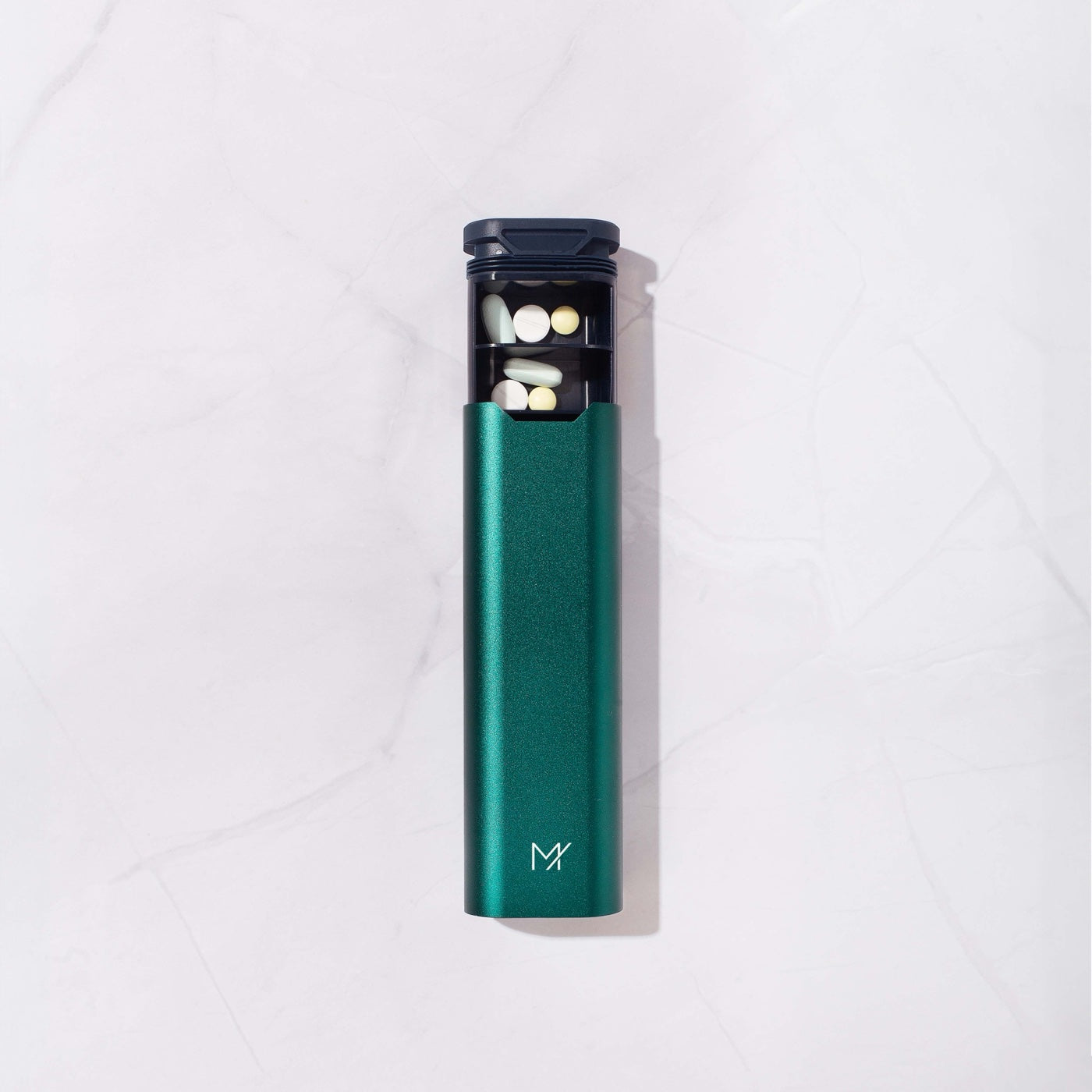 A forest green Mannox Once-Daily from above with the tray part-open and pills in the first compartments